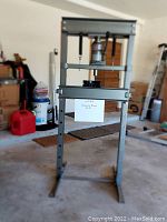 Full front view of the 20 ton hydraulic shop press in a garage setting showing the entire press frame and hydraulic jack.