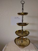 Photo showing four tier serving stand with gold tone hammered plates and chrome handle and support.