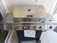 Frontal view of the Nexgrill stainless steel gas grill showing the lid, control panel with 6 knobs, and side burner.