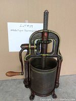 Front view of the antique cast iron sausage stuffer showing Simmons Hardware patent details and large screw press with wooden handle