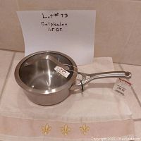 Calphalon 1.5-quart stainless steel saucepan with glass lid and stainless steel rim, new condition with original tags visible.