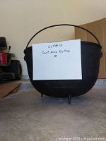 Front view of cast iron kettle cauldron showing three legs and handle with visible welded repair on one leg.