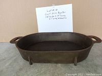 Rectangular cast iron roaster with handles on both ends shown from front angle to display shape and size.