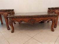 Photo showing the coffee table and two lamp tables arranged on a tiled floor, highlighting wood carved legs and registered base details.