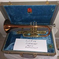 Top view of brass Conn Coronet cornet inside its blue velvet lined case along with handwritten note.