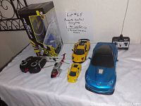 Photo of the lot including a blue remote control Corvette with controller, remote control helicopter with controller, and two yellow diecast Ferrari cars.
