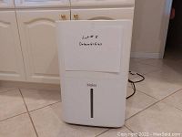 Front view of the white Haier dehumidifier with water level indicator visible and note 'Lot #5 Dehumidifier' attached.