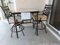 Patio set showing two large metal chairs with cream cushions and square table with ceramic top and metal legs