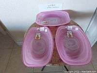 Photo showing 3 pink glass swirl design serving platters with tags, displayed on table.