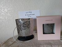 Silver ambient lamp on black base and second lamp in box with decorative lamp window
