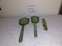 Front view of the green and gold vintage mirror, brush, and tortoiseshell comb set on white surface with note behind