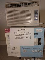 WINTAIR 5400 BTU window air conditioner unit on top of its original cardboard packaging, showing front vents and control panel with buttons and a display screen