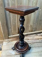 Full view of antique wooden stand showing square top, twisted ebony spiral column, and circular base with ball and claw feet.