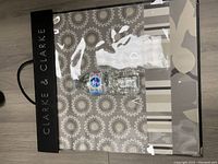 Cover of the Clarke and Clarke fabric book shown alongside water bottles for scale, displaying the brand name and clear plastic sleeve with fabric samples visible