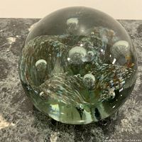Front view of large spherical glass paperweight with controlled bubbles and colored swirls inside.