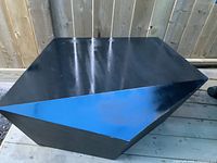 Top and side views of the large geometric black table showing its polygonal shape and black paint with some nicks and chips.