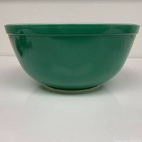 Side profile of large green Pyrex mixing bowl showing smooth exterior and rim detail.