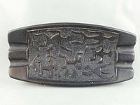 Photo showing a black lava tiki ashtray with tribal petroglyph carvings and stepped ridge sides viewed from above.