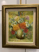 Full front view of the floral oil painting in gold frame against a neutral background with water bottle for size reference.