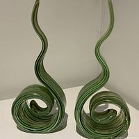 Front view of both green Murano scroll sculptures side by side