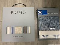 Pair of Roma and Kravet fabric sample books shown closed from front