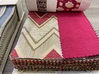 Close-up of fabric swatches in pink and beige chevron and geometric patterns from Schumacher fabric book