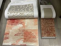 Two open fabric books displaying fabric samples including floral and abstract patterns in warm and neutral tones.