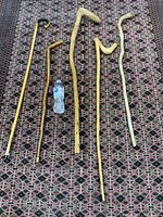 Five vintage natural wood canes laid on patterned rug with water bottle for scale