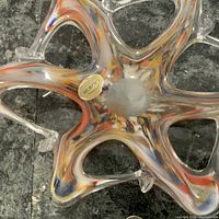 Top view showing colorful swirled interior, star-like open form and original Murano label.