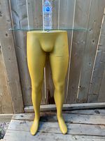 Front view of vintage 1980s Silent Bartender bar stand with yellow leg-shaped base and glass top (glass not included).