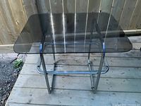 Square vintage smoked glass top with rounded corners mounted on chrome metal base with rectangular frame and crossbars. Surface rust present on chrome base.