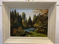 Front view of the framed oil painting showing the landscape scene with the water and trees.