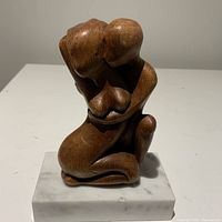 Front view of vintage teak abstract embracing couple sculpture on white marble base showing smooth finish and curves.