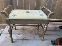 Front and side views of the vintage needlepoint bench showing wooden gold-toned frame and floral needlepoint seat.