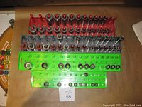 Photo showing multiple rows of sockets held in red, gray, and green plastic racks on a beige surface, with sockets of various sizes and types arranged neatly.