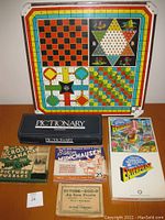 Photo of antique game board with four game patterns including checkerboard and star shape, surrounded by various boxed vintage games and puzzles.