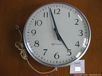 Edwards round 13 inch electric wall clock with white face, black numbers, and a power cord.