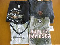 Four Harley Davidson t-shirts laid flat on table showing front designs and colors.