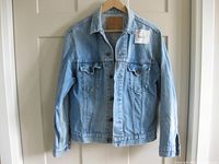 Front view of 1980s Levi's men's jean jacket, size 42, showing light blue faded denim with button front and chest pockets.
