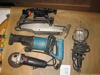 Vintage Craftsman sawzall, Makita sawzall, Jobmate grinder, and trouble light displayed on a surface.