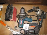 Photo showing Black & Decker drill, sander and scroll saw alongside Bosch impact tool on a table.