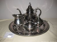 Full view of silver plated tea set including coffee pot, creamer, sugar bowl, milk pitcher all on the matching tray.