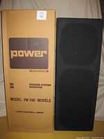 Photo of one speaker in a black fabric cover with original cardboard box saying Power Acoustics Model PW 240, Toronto/Montreal, Canada.