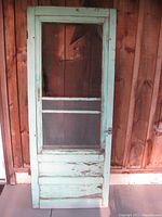 Full front view of the vintage wood screen door showing paint wear and overall condition.
