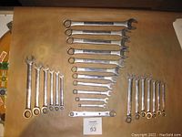 Layout of 24 assorted wrenches arranged by size and brand on flat surface.