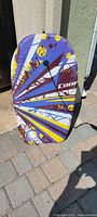 Front side of bodyboard showing colorful graphic design with purple, yellow, white, and brown colors.