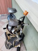 View of golf bag containing golf clubs and attached orange ball retriever
