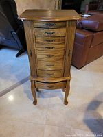 Front view of vintage wooden jewelry cabinet with 7 drawers and decorative handles