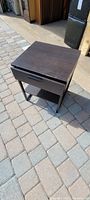 Dark brown Ikea Trysil Model 1601 end table shown outside on a paved ground, looking down at the top and side showing drawer and bottom shelf.
