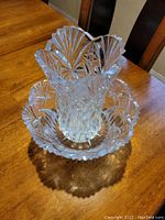 Photo of clear crystal vase with scalloped rim and deeply cut arches, stars and fan pattern elevated on a wooden table